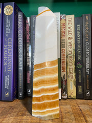 A banded orange calcite generator placed on a wooden surface with a row of books in the background.