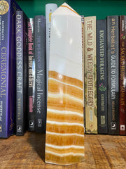 A banded orange calcite generator placed on a wooden surface with a row of books in the background.