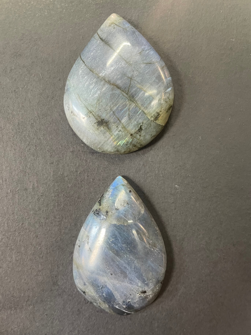Two teardrop-shaped Labradorite stones on a gray background