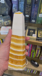 A banded orange calcite generator placed on a wooden surface with a row of books in the background.