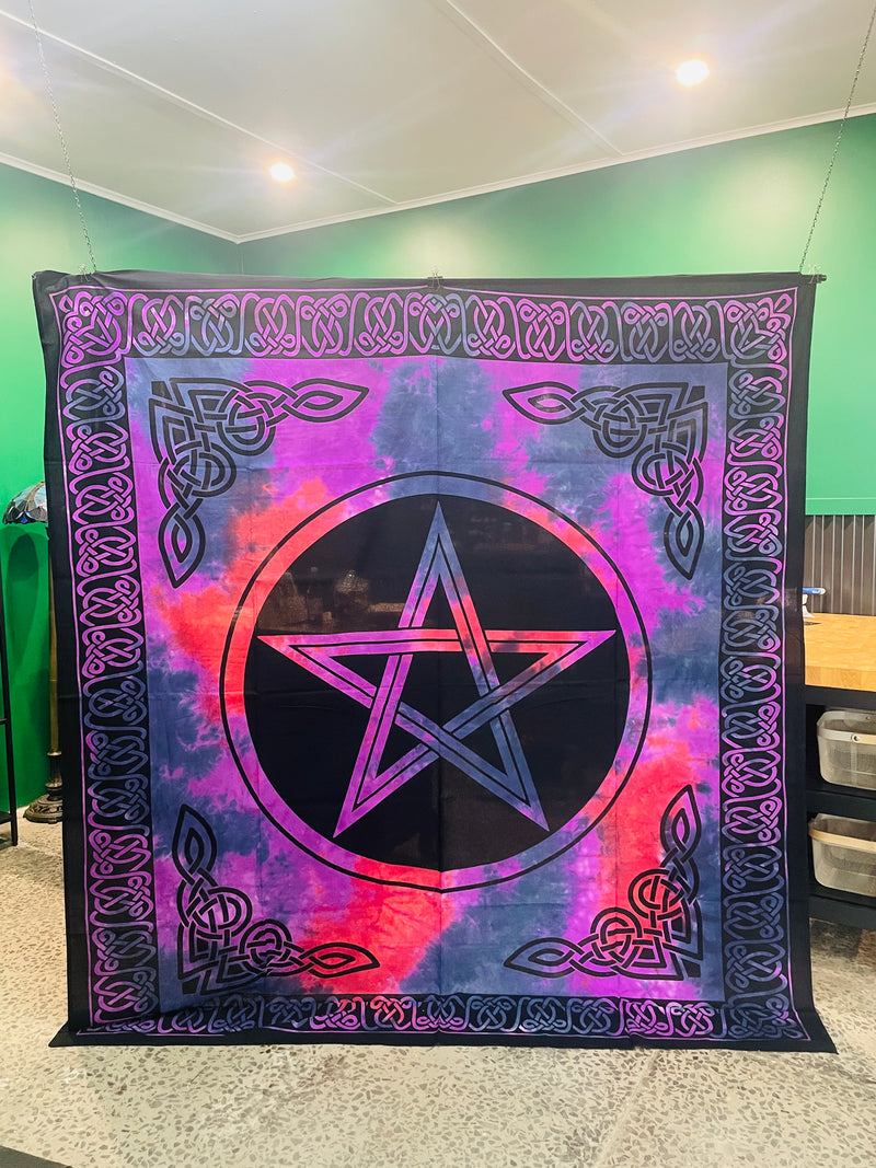 A square tapestry featuring a central pentagram inside a circle, surrounded by a purple and pink tie-dye background and an ornate black Celtic knot border, hanging on a wall in an indoor room.