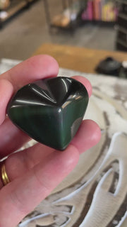 video of hand holding a rainbow obsidian heart