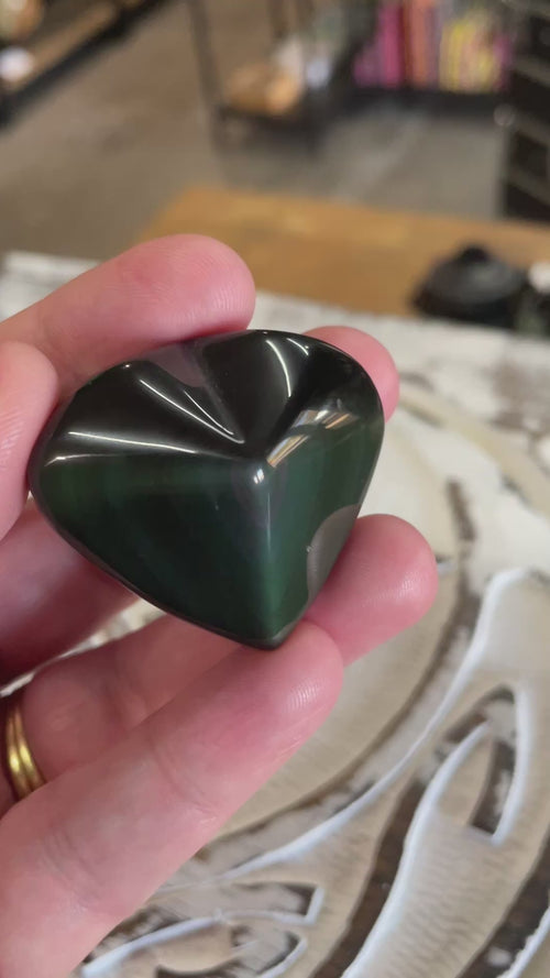 video of hand holding a rainbow obsidian heart